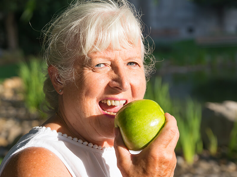 Elderly woman eating healthy outdoors