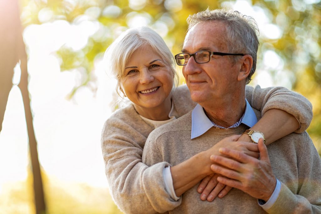 Elderly couple embracing in autumn park