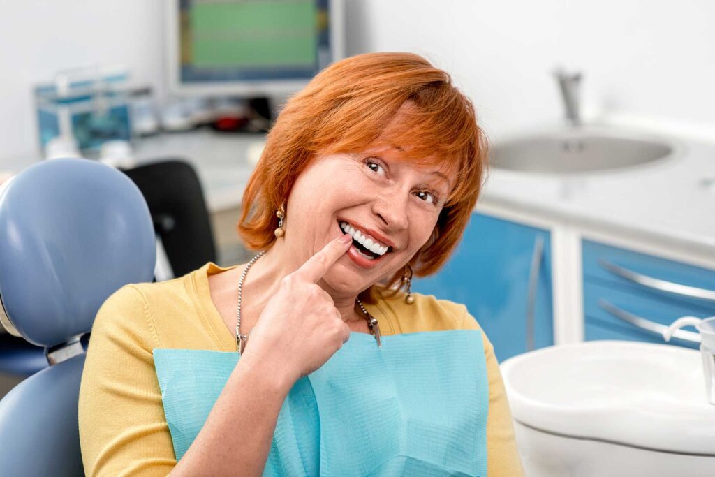 woman pointing to her teeth that had been finished woman pointing to her teeth that had been finished