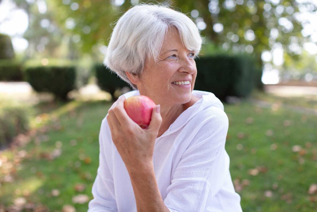 senior lady outside eating an apple senior lady outside eating an apple