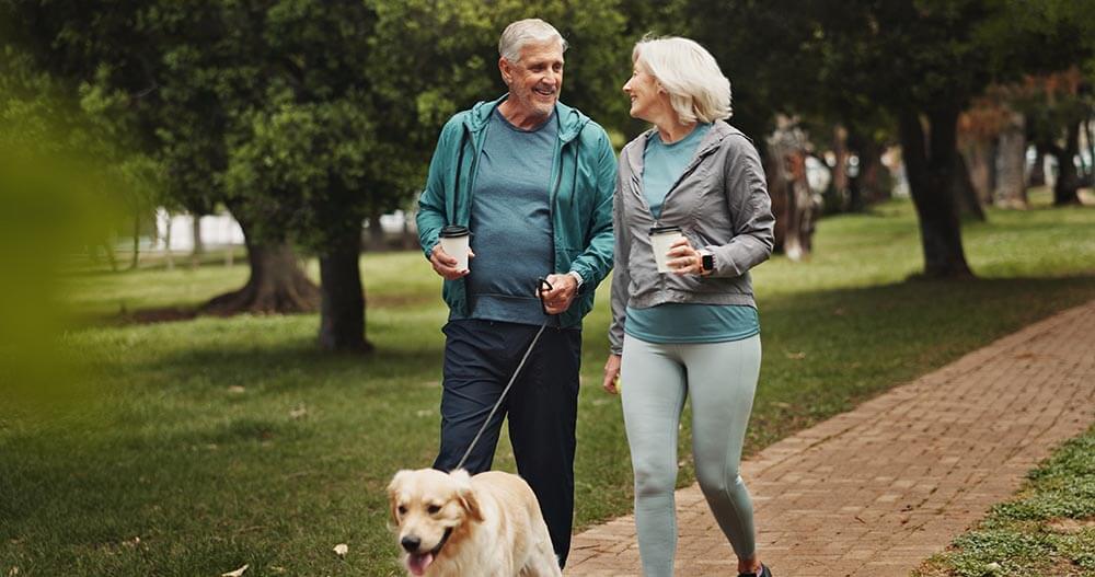 old couple and walking dog in park together